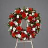 Circular floral wreath on a wooden easel with red, white, and orange flowers