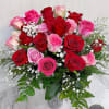 Arrangement of red and pink roses with white filler flowers in a textured glass vase