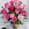 Tall glass vase of hot pink and light pink roses with white filler flowers and a pink ribbon