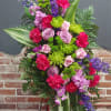 Standing floral spray with pink roses, carnations, and purple blooms