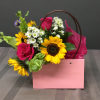 Pink gift bag with sunflowers, roses, and white daisies