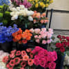 Assorted rose bouquets in black buckets with blue delphinium and white hydrangeas