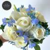 Round bouquet of white roses with light blue flowers and a pearl accent in one rose.