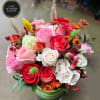 Mixed arrangement of pink, red and white roses with accent blooms in a green striped vase