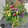 Mixed tulip bouquet in a glass vase with a pink ribbon