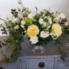 Cream and white floral arrangement in a clear pedestal vase