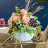 Peach roses and cream hydrangea in a white vase with dried accents