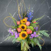 Bouquet of sunflowers, pink roses, and purple flowers in a glass vase