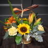 Basket arrangement with sunflowers, lilies, and carnations tied with a ribbon