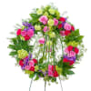 Bright standing wreath of pink roses, green and red blooms on a metal easel.