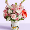 Pink and white flower arrangement in a Mickey Mouse tin with a red heart topper