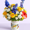 Bouquet of yellow roses, white daisies, and blue flowers in a Mickey Mouse tin