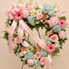 A soft heart-shaped sympathy wreath crafted in pastel pinks, blues, whites, and