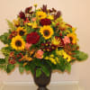 a beautiful autumn arrangement bursting out of a brown and copper urn.