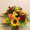 A autumn vase filled with a mix of flowers in including sunflowers