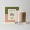 Lit scented candle in a glass tumbler with its box behind it