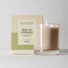 Lit white tea and bergamot candle beside its box