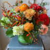 Mixed bouquet of orange, red, and peach flowers in a glass vase