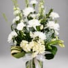 White floral arrangement in a glass vase with a ribbon bow