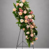 Tall floral spray with peach and white roses on a black stand