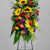 Tall standing floral spray with sunflowers, roses, and carnations on an easel