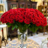 Large bouquet of red roses in a clear glass vase with a striped ribbon