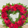 Heart-shaped wreath of red roses and carnations with green foliage