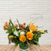 Orange roses and lilies arranged in a green vase