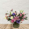 Mixed pink and purple flower arrangement in a glass vase