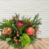 Mixed bouquet with pink blooms and a magenta protea in a low vase