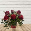 Red roses in a red glass vase with baby's breath