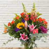 Colorful mixed bouquet in a glass vase with sunflowers, roses, lilies, and snapdragons