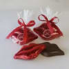 Two red ribbon-tied gift bags with chocolates and a red foil lips-shaped candy