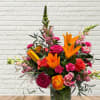Bright mixed bouquet with orange lilies and pink roses in a glass vase