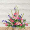 Pink roses and lilies arranged with purple accents in a clear vase.