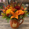 Autumn bouquet in a brown mug-shaped vase with orange lilies and yellow blooms