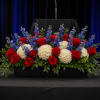 Red roses, white hydrangeas, and blue flowers in a black rectangular container
