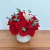 Red roses in a white vase with a white orchid bloom