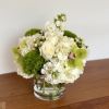 White floral arrangement in a clear glass vase with bright green accents