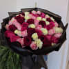 Bouquet of pink, red, and cream roses wrapped in black paper