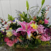 Large mixed floral arrangement with pink lilies and roses in a low container