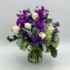 Purple and white flowers arranged in a clear glass vase
