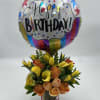 Birthday balloon above a bouquet of yellow calla lilies and peach roses in a vase