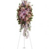 Standing floral spray with pink and purple flowers on a white easel