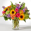 Mixed bouquet of roses, sunflowers, and purple blooms in a glass vase