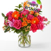 Pink and orange bouquet in a glass vase with a birthday balloon