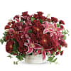 Red and pink mixed flower arrangement in a white container
