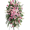 Tall pink funeral spray on a stand with lilies and roses