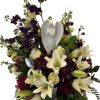 White lilies and purple flowers arranged in a round vase with a white angel ornament