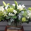 White lilies and green blooms in a clear glass vase